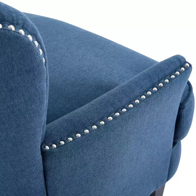 Un fauteuil inclinable capitonné de style vintage orné de rivets et de pieds en bois